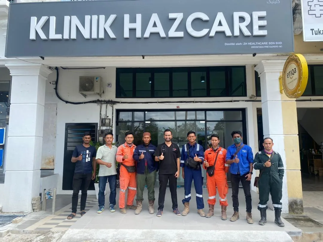 Dr Zafri (di tengah, jubah gelap) bersama pekerja industri yang datang untuk penilaian perubatan ruang terkurung, di hadapan Klinik Hazcare.